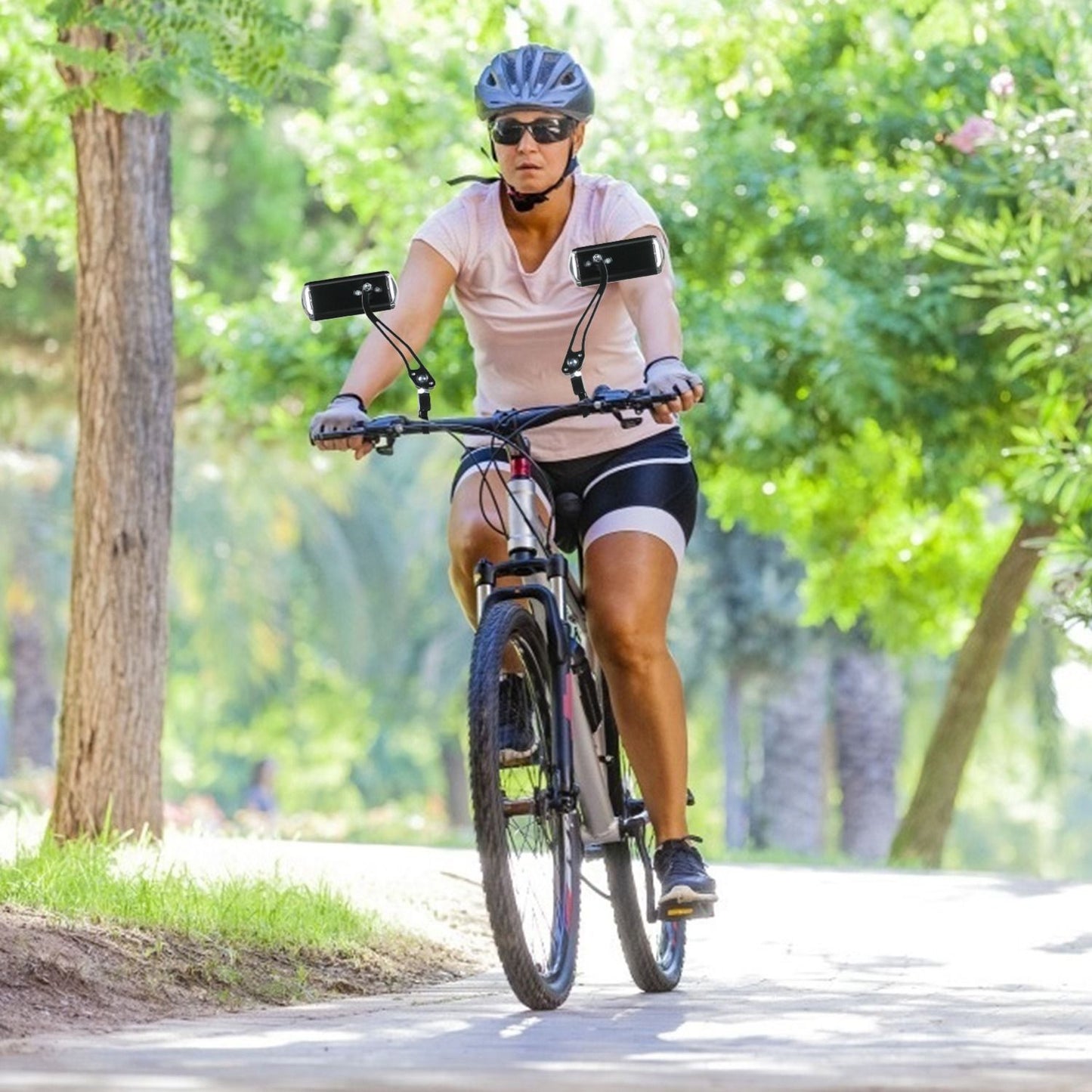 Woman riding a mountain bike on a scenic path, wearing a helmet and cycling gear, surrounded by lush greenery.