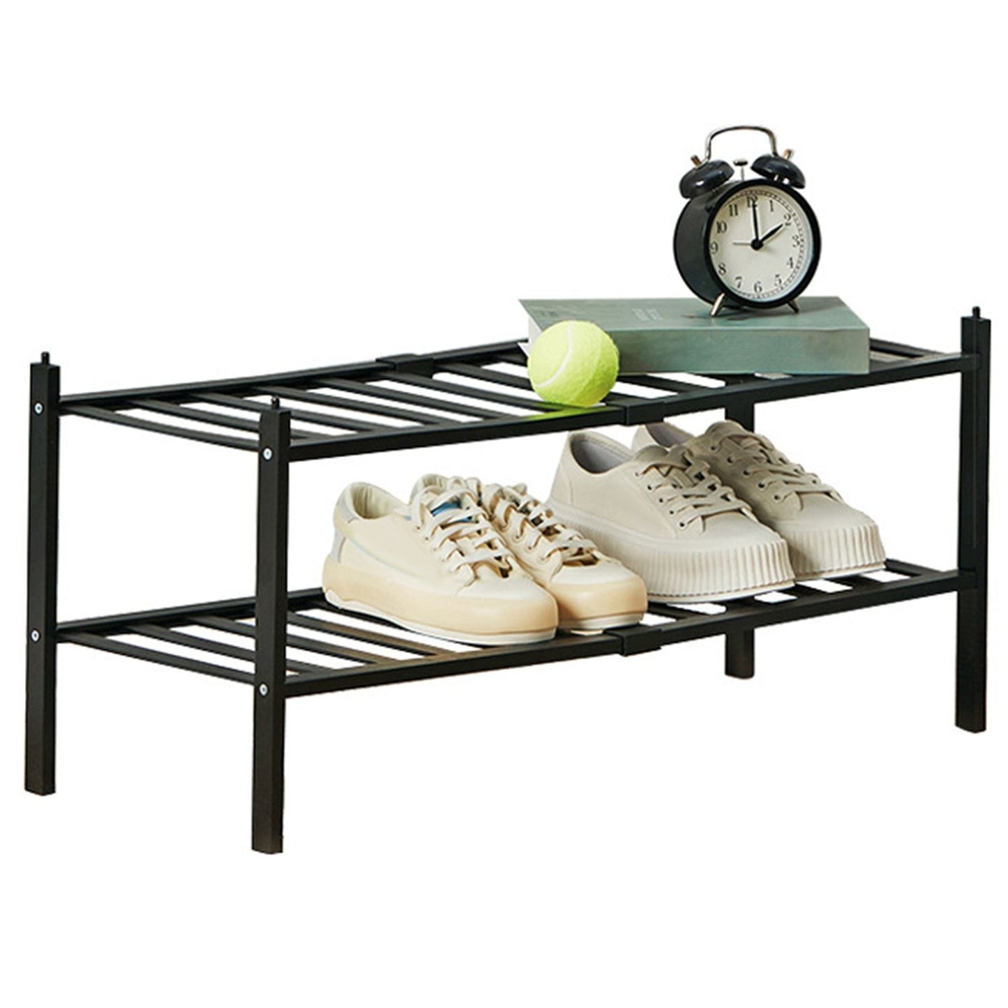 Two pairs of stylish beige sneakers displayed on a black shoe rack with a green tennis ball, a classic black alarm clock, and an open book on top.