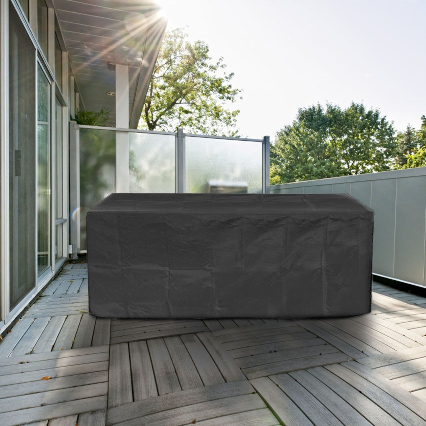 Outdoor furniture cover in a stylish black color, placed on a wooden patio, with sunlight filtering through nearby trees.
