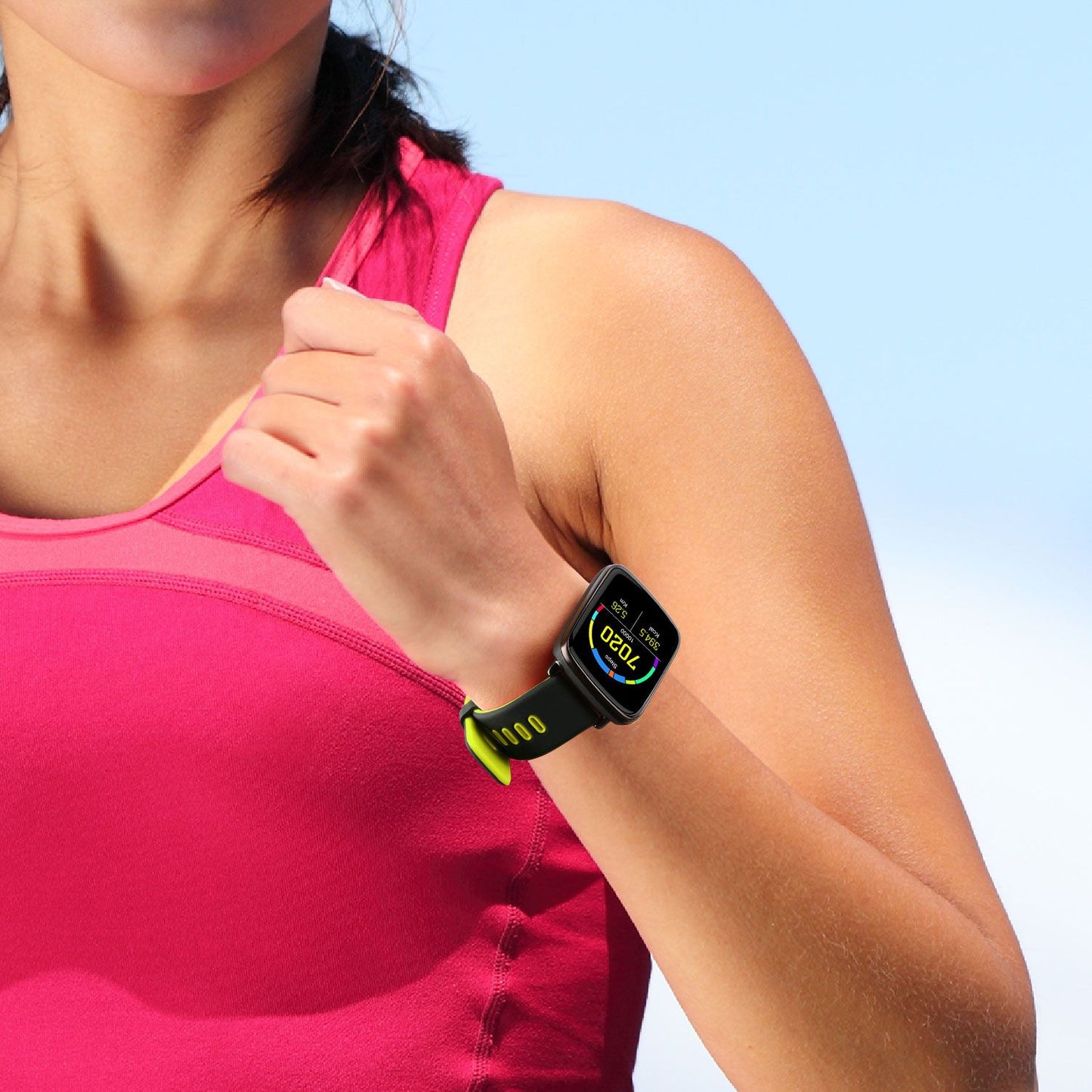 Close-up of a woman's wrist wearing a black fitness smartwatch with a bright yellow band, displaying heart rate and workout metrics, against a sunny blue sky background.