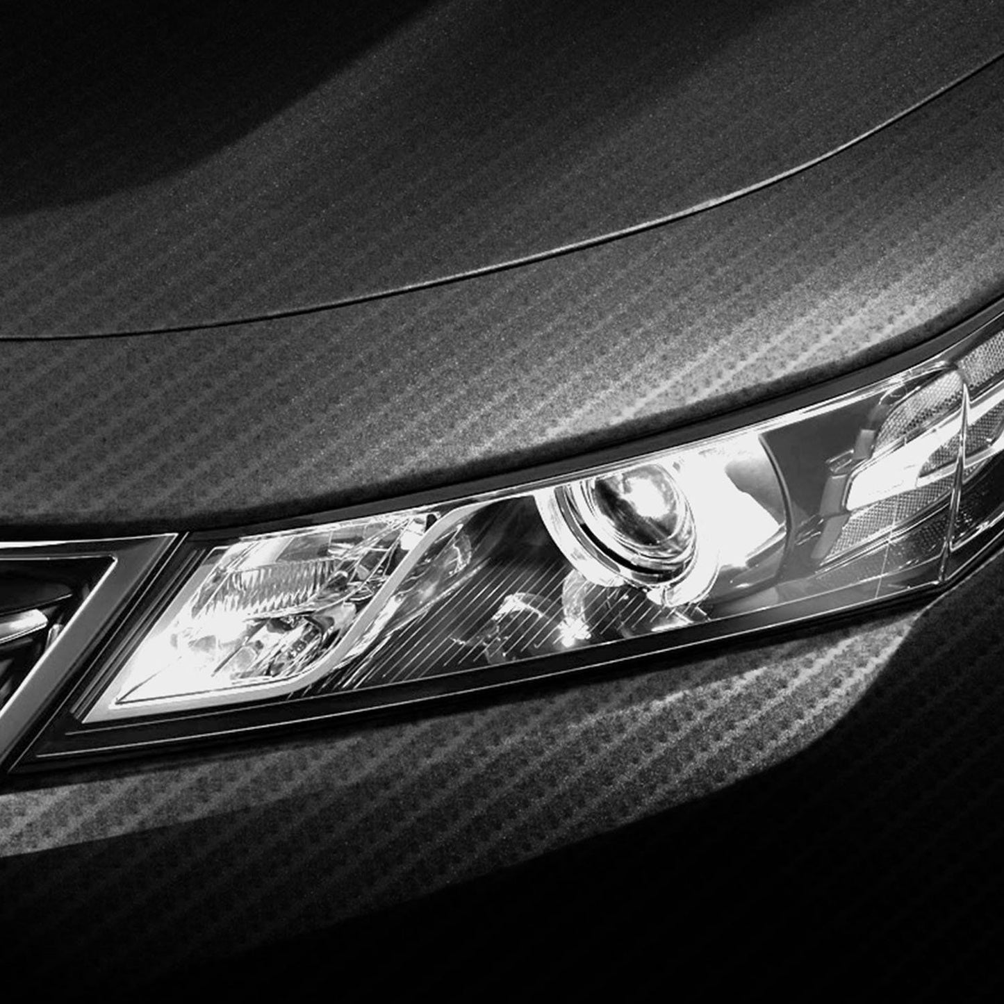 Close-up of a car's sleek front headlight design featuring modern LED lighting against a textured black hood, highlighting automotive elegance and innovation.