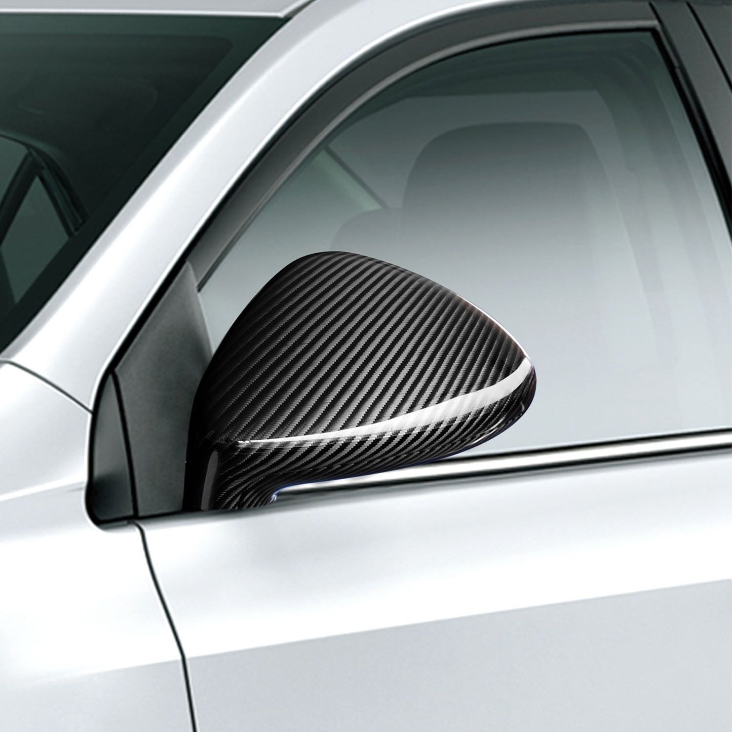 Close-up of a sleek black carbon fiber car side mirror on a silver vehicle, showcasing a modern and stylish automotive accessory.