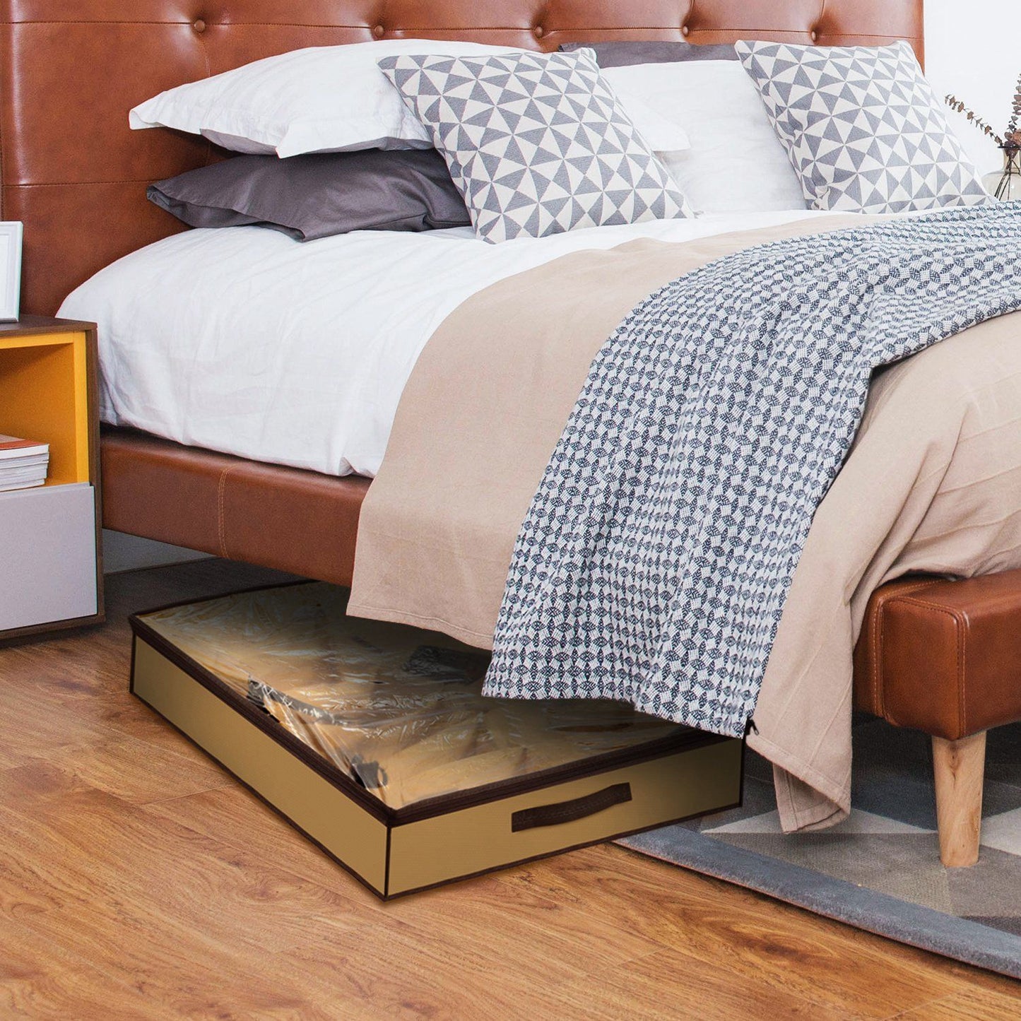 Under-bed storage drawer with a golden finish, placed beneath a stylish brown leather bed, providing an organized and space-saving solution for bedding and other items, featuring a clear plastic cover for protection.