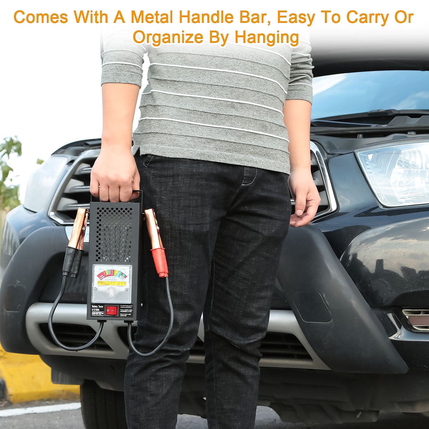 Person holding a portable jump starter with a metal handle bar and color-coded cables, standing near a parked vehicle, showcasing convenience and organization for emergency car battery needs.