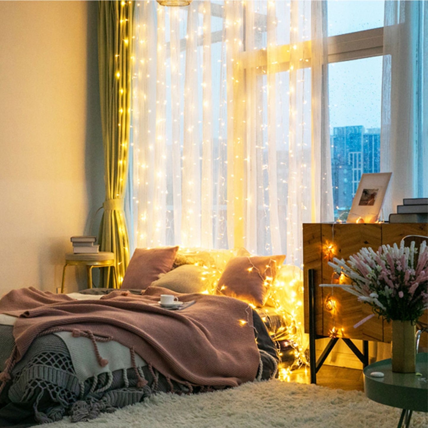 Cozy bedroom with string lights, plush bedding, and decorative accents, featuring large windows and a warm, inviting atmosphere.
