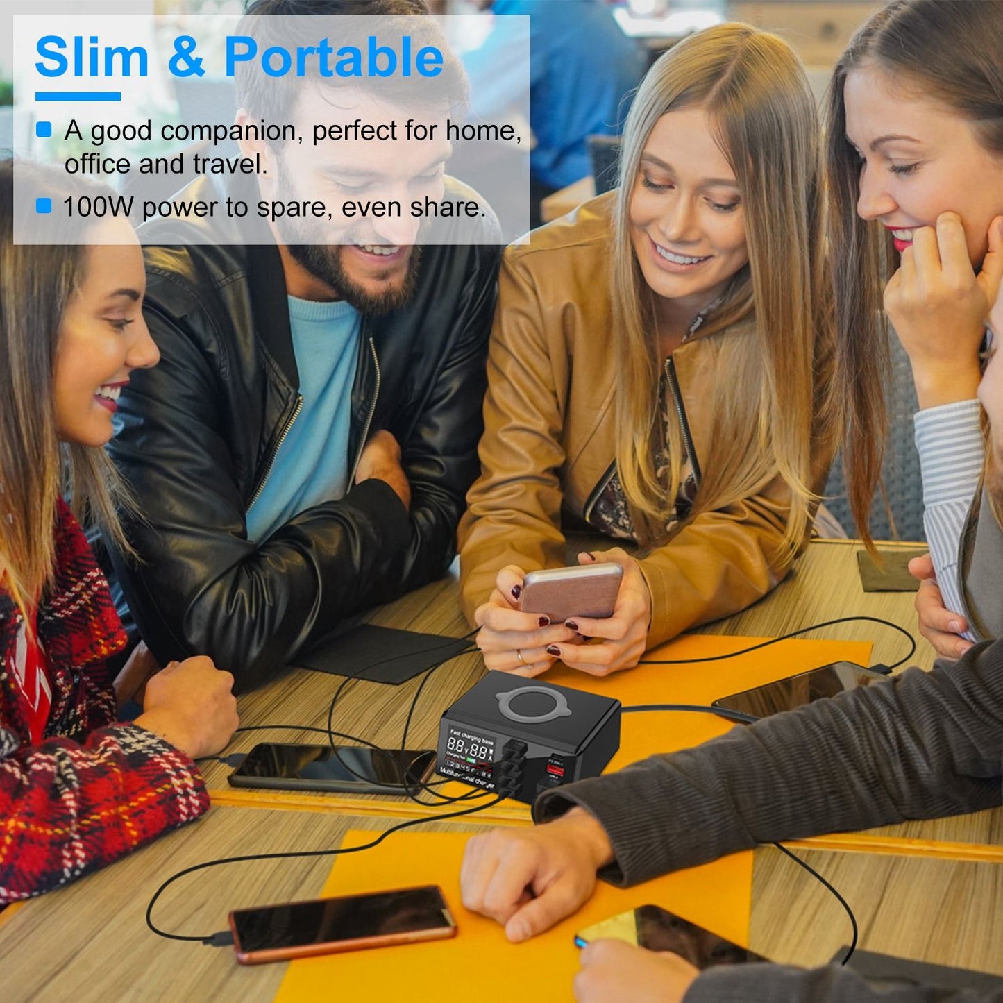 Portable power station charging multiple devices on a table surrounded by people, ideal for home, office, and travel use.