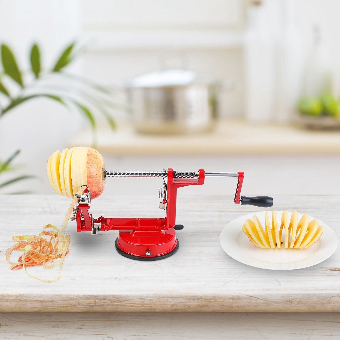 Red apple peeler with sliced apple on a plate, showcasing an efficient kitchen tool for easy apple preparation.