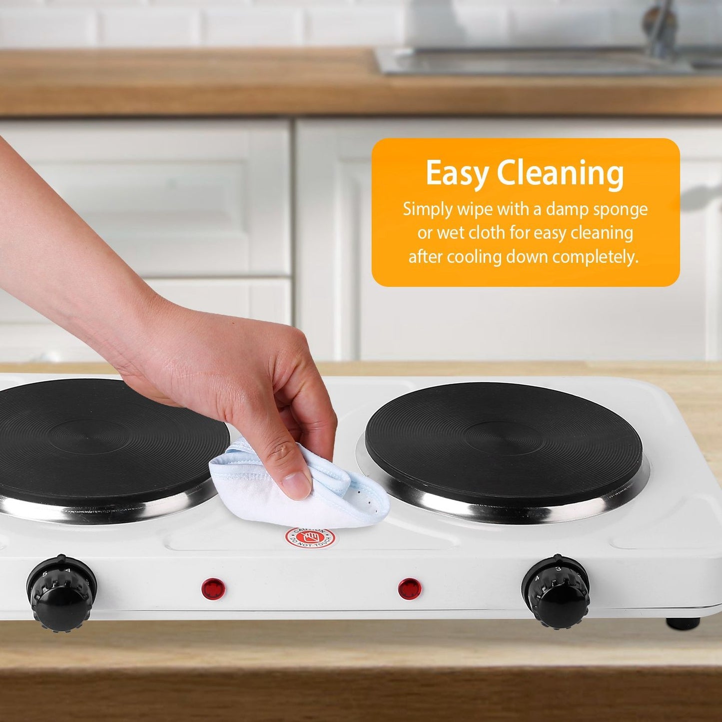 A hand wiping a double electric burner with a cloth, showing easy cleaning features, in a modern kitchen setting.