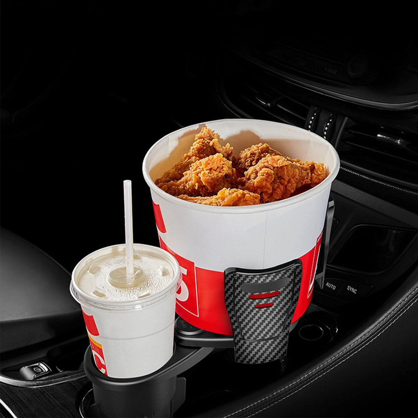 Large bucket of crispy fried chicken and a soft drink in a car cup holder, highlighting a convenient on-the-go meal option.