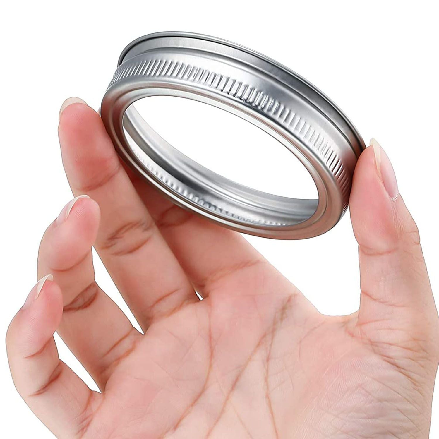 Hand holding a stainless steel canning lid with a textured rim, ideal for preserving homemade jams and pickles.