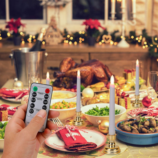 Hand holding a remote control in front of a beautifully set festive dinner table featuring a golden roasted turkey, various side dishes, candles, and holiday decorations.