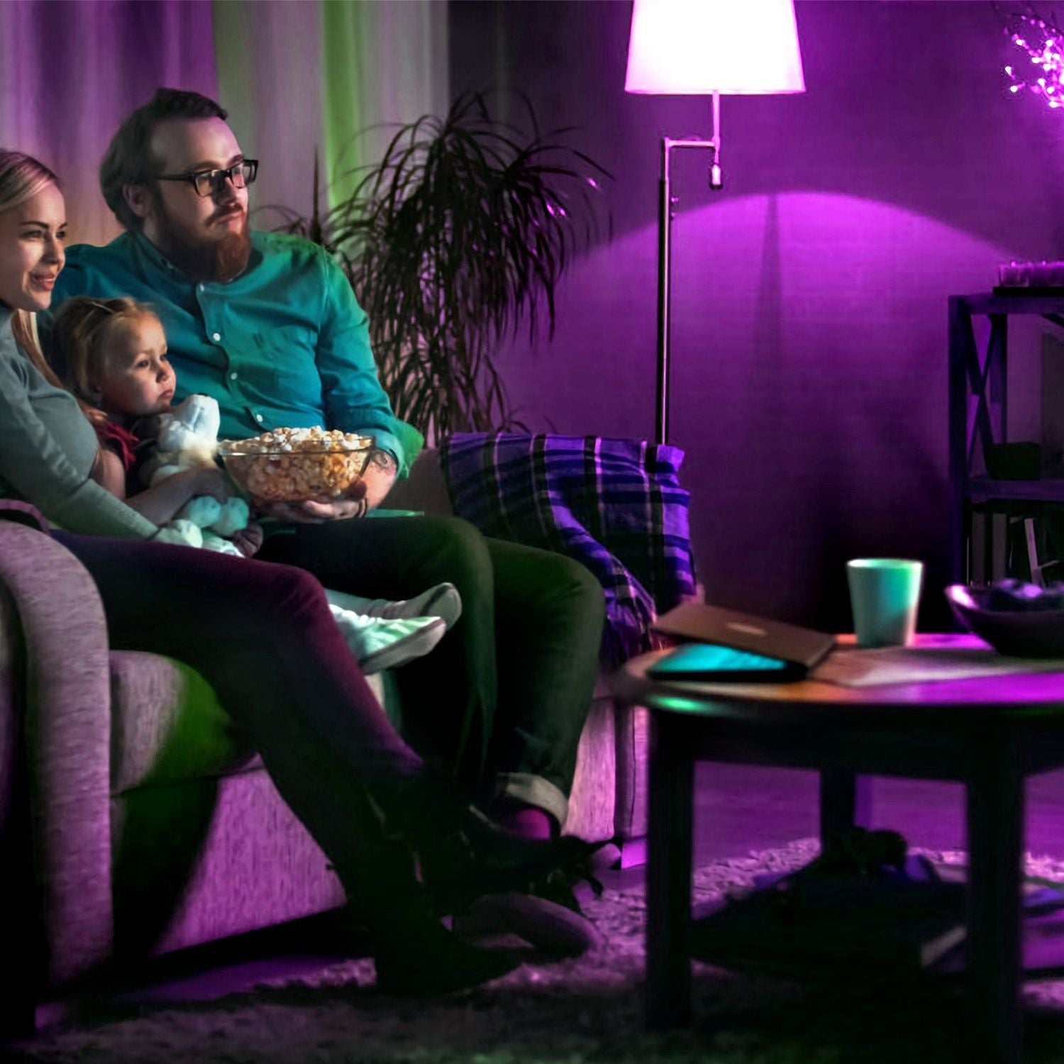 Family movie night on a cozy couch, enjoying popcorn in a warmly lit living room with purple accents, featuring a coffee table and a plush rug.
