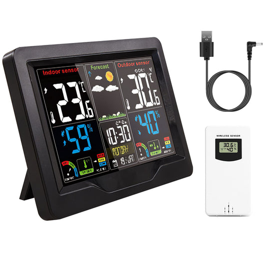 Digital weather station display with indoor and outdoor temperature, humidity readings, weather forecast icons, and outdoor wireless sensor, featuring a USB charging cable.