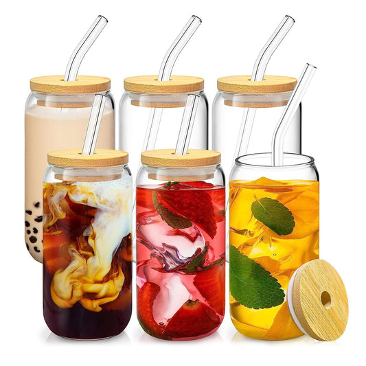 Set of five clear mason jars with bamboo lids and reusable straws, filled with colorful drinks including bubble tea, iced coffee with cream, fruity sparkling beverage, and herbal tea with mint leaves.