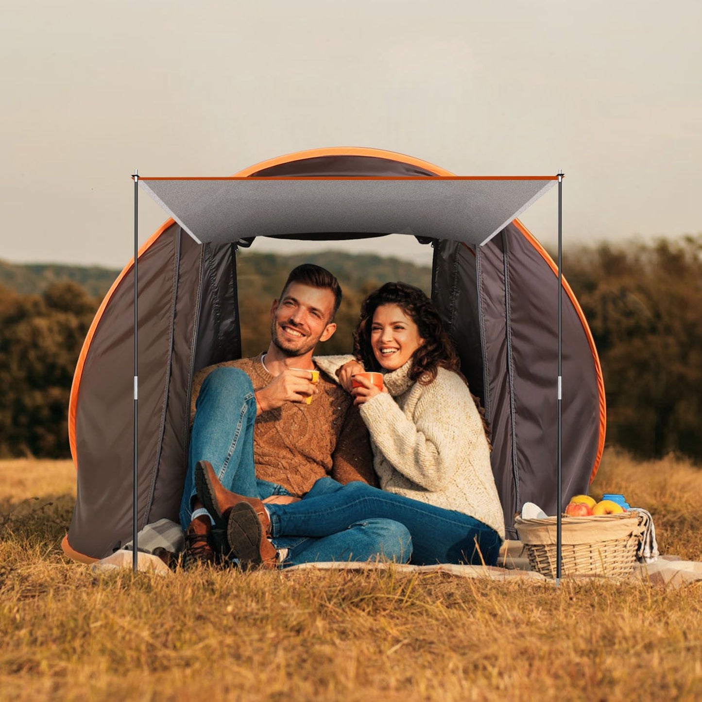 Couple relaxing inside a portable tent on a grassy field, enjoying drinks together with a picnic basket nearby, showcasing outdoor camping comfort and style.