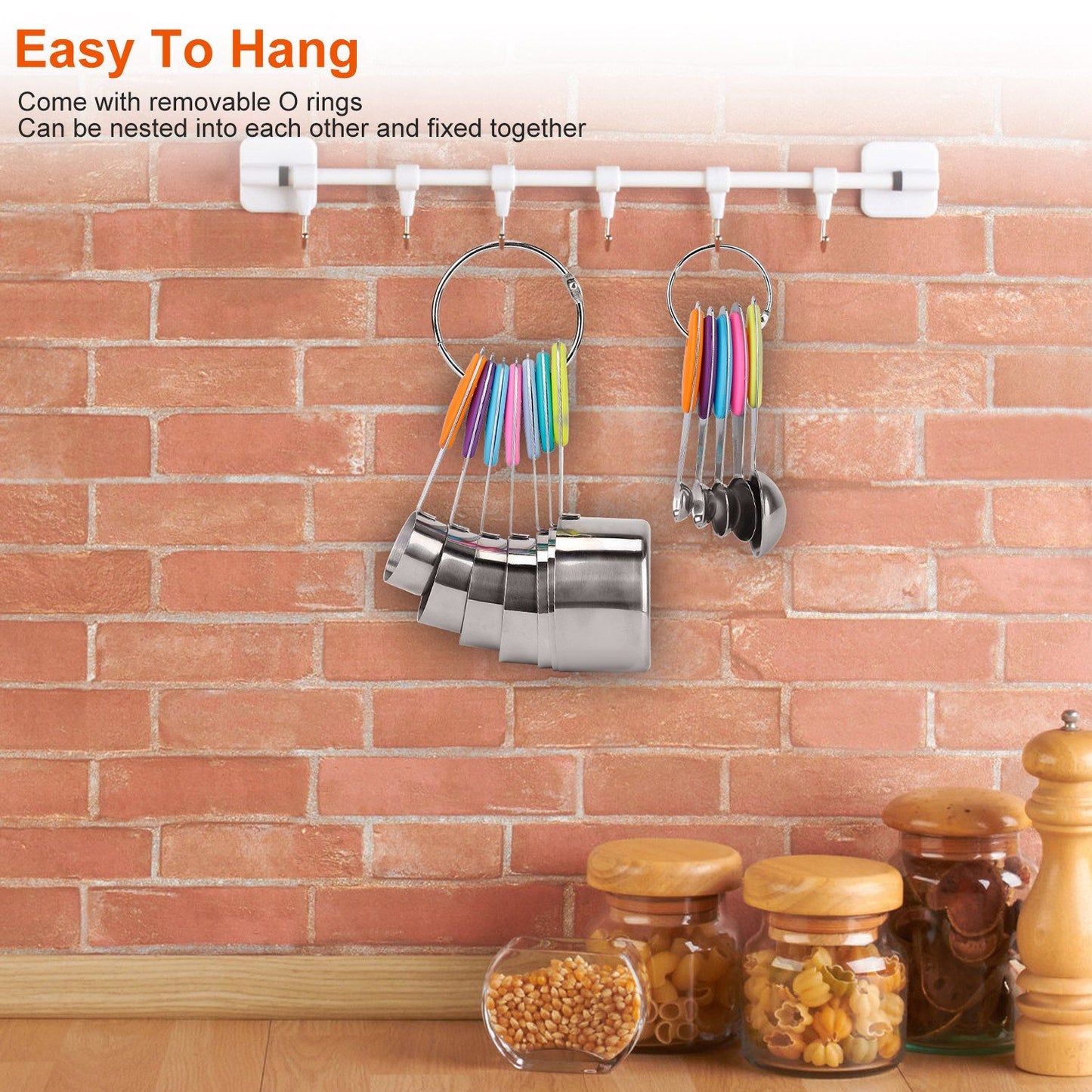Stainless steel measuring cups and colorful measuring spoons displayed on a wall-mounted rack in a kitchen setting with a brick background, showcasing easy organization and accessibility.
