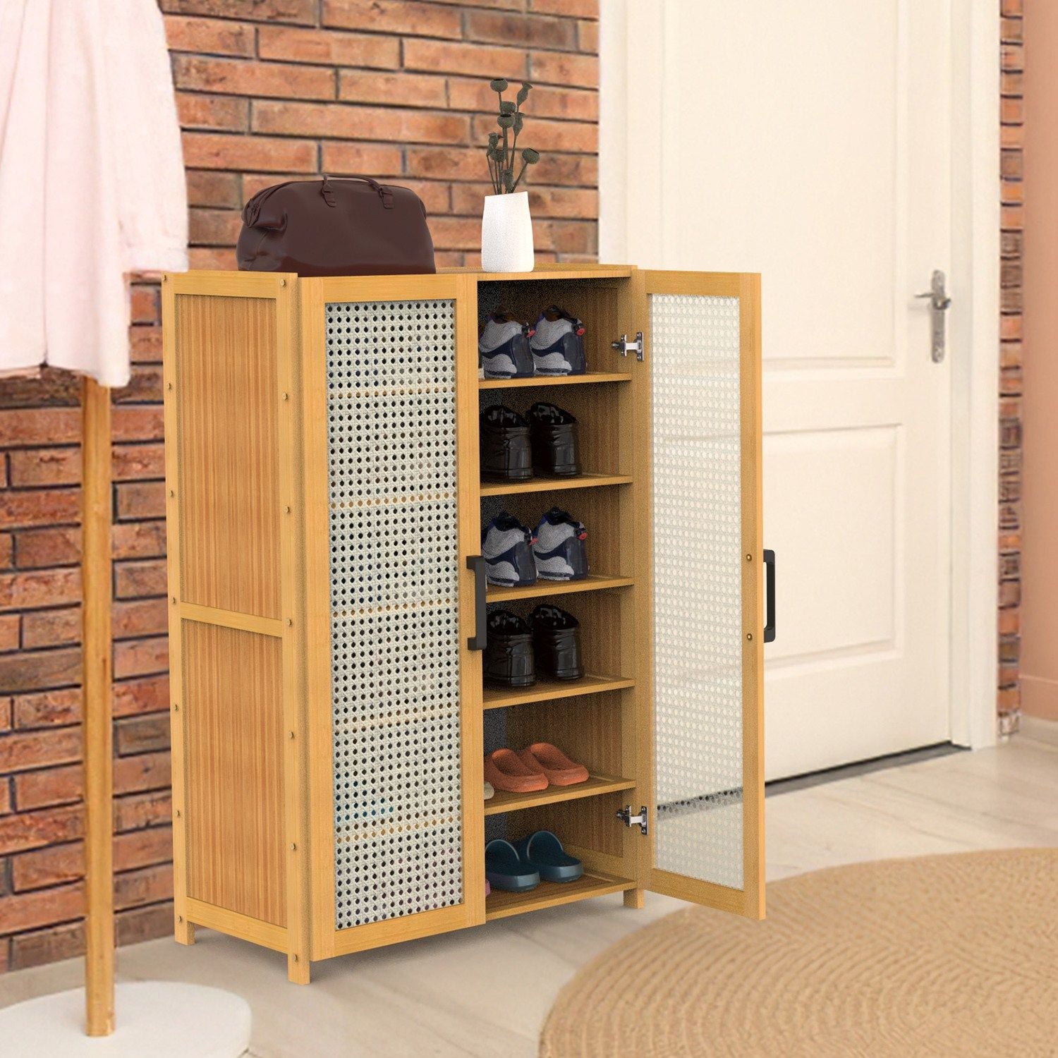 Modern wooden shoe storage cabinet with mesh doors, featuring multiple shelves filled with various shoes and a stylish handbag on top, set in a cozy entryway with brick walls.
