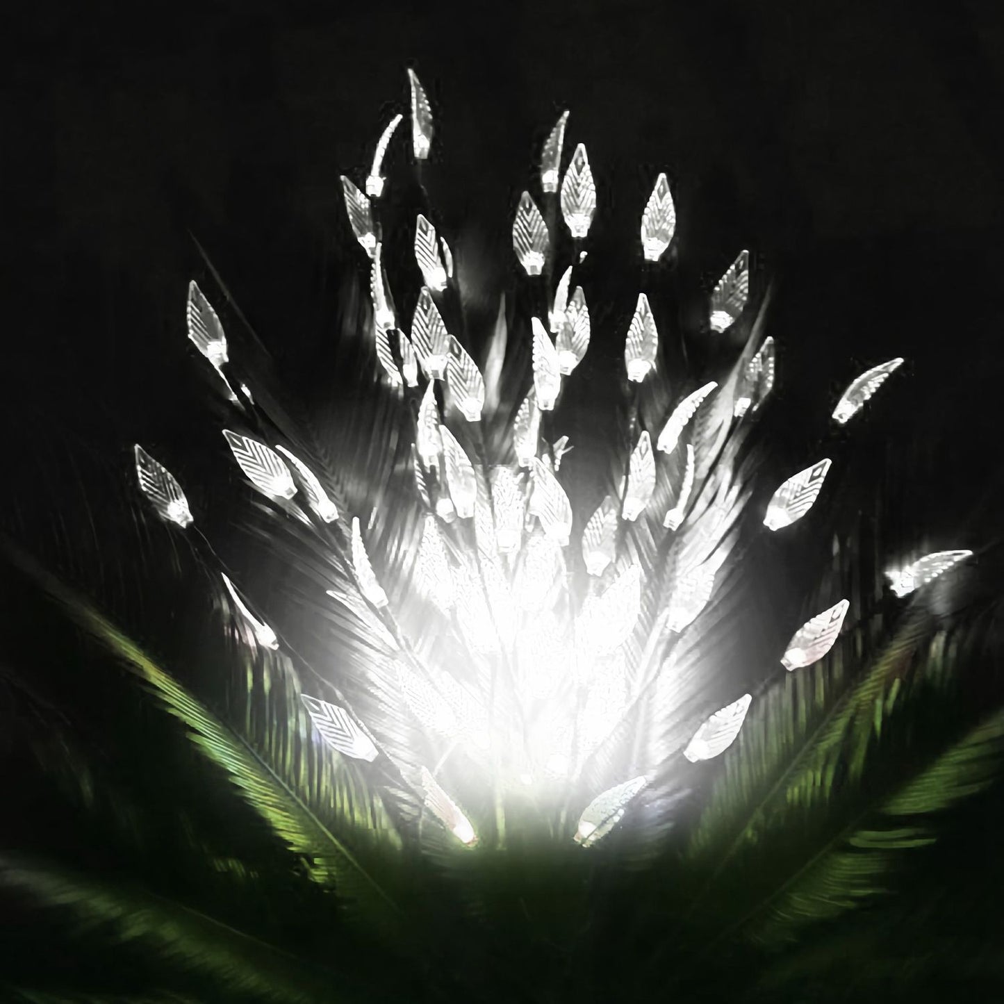 LED feather light display emitting a bright white glow against a dark background, surrounded by green foliage for an elegant decorative effect.