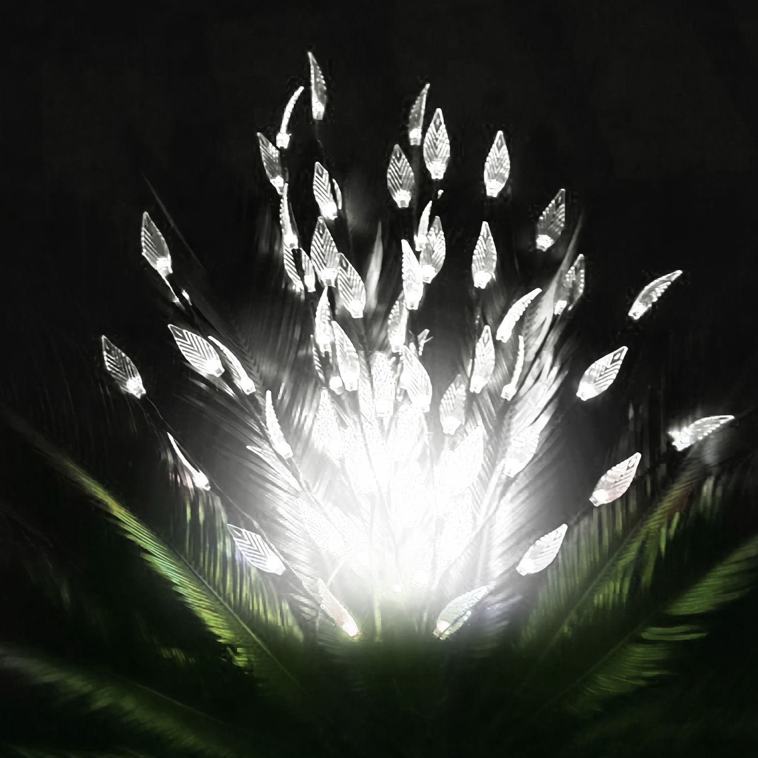 LED feather light display emitting a bright white glow against a dark background, surrounded by green foliage for an elegant decorative effect.